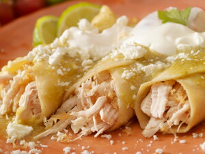 Tres burritos de pollo con salsa en un plato marrón