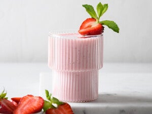 Un vaso contiene batido de fresa y la fruta de decoración