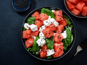Un bowl que contiene cubos de sandía, espinacas y queso