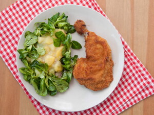 Un plato que contiene pollo empanizado con una ensalada