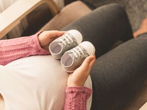 Mamá embarazada de un bebé arcoíris cogiendo unos zapatitos.