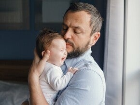 Papá sosteniendo a bebé llorando para ayudarle a eructar