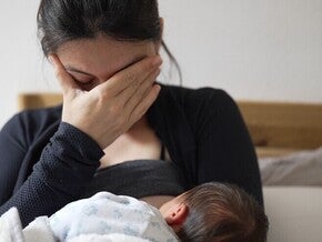 Madre amamantando, con gesto de angustia, reflejando posibles signos de depresión posparto