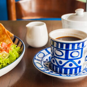 Quesadilla de Espinacas con Guacamole y Café Una taza blanca y azul que contiene café y al lado un plato con ensalada verde y quesadillas