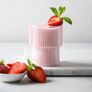 Batido Cremoso de Fresas Un vaso contiene batido de fresa y la fruta de decoración