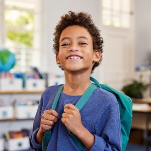 Niño con mochila sonriendo en su nuevo colegio