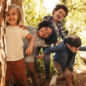 Niños preescolar corriendo y sonriendo al aire libre, ilustrando los beneficios de la actividad física