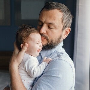 Papá sosteniendo a bebé llorando para ayudarle a eructar