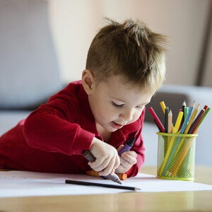 Niño pequeño coloreando una hoja blanca