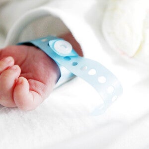Mano de bebé recién nacido con pulsera de hospital