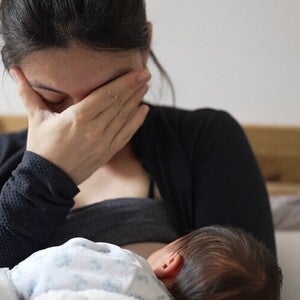 Madre amamantando, con gesto de angustia, reflejando posibles signos de depresión posparto