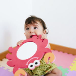 Representación de los síntomas cuando salen los dientes a los bebés en un escenario en el que el pequeño está mordiendo un juguete