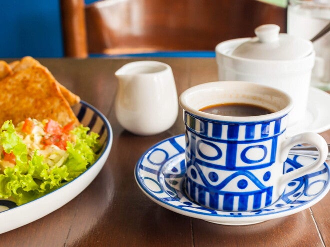 Quesadilla de Espinacas con Guacamole y Café Una taza blanca y azul que contiene café y al lado un plato con ensalada verde y quesadillas
