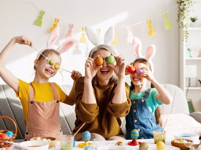 Padres y niños celebrando Pascua, cubriendo sus ojos con huevos de colores de forma divertida.