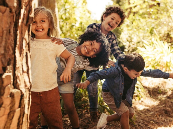 Niños preescolar corriendo y sonriendo al aire libre, ilustrando los beneficios de la actividad física