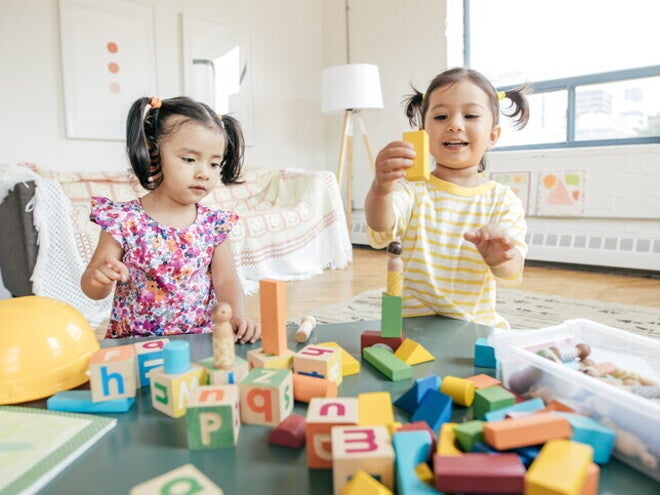 Grupo de niños preescolares riendo y jugando juntos, mostrando interacción social positiva.