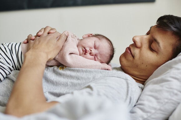 Un bebé durmiendo en el pecho de su padre.
