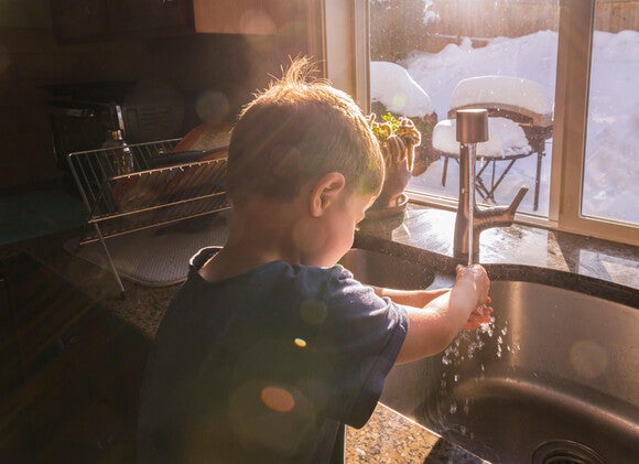 Niño pequeño lavándose las manos para prevenir la estomatitis infantil 