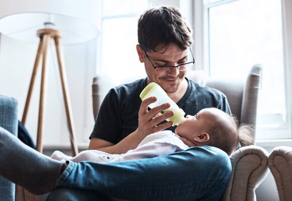 Un bebé siendo alimentado por su padre. 