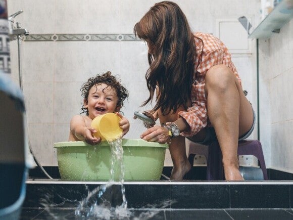 Niño pequeño divirtiéndose con su mamá a la hora del baño.