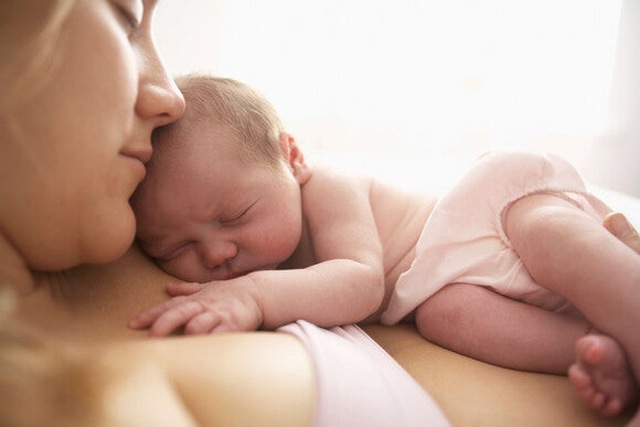 Bebé recién nacido acostado durmiendo sobre el pecho de su mamá