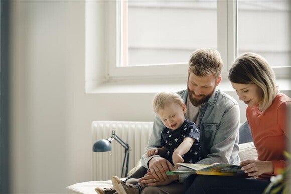 Padres fomentando hábitos de estudio en su hijo mediante la lectura en casa.