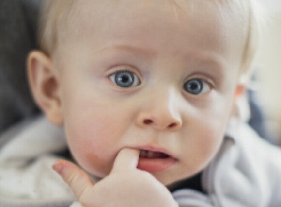 Representación de los síntomas cuando salen los dientes a los bebés en el que un pequeño muerde su dedo por incomodidad
