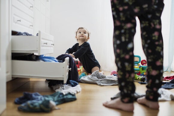 Niño pequeño sacando su ropa de bebé del armario